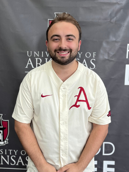 Image of Colin in front of the Bumpers College backdrop wearing a white U of A shirt