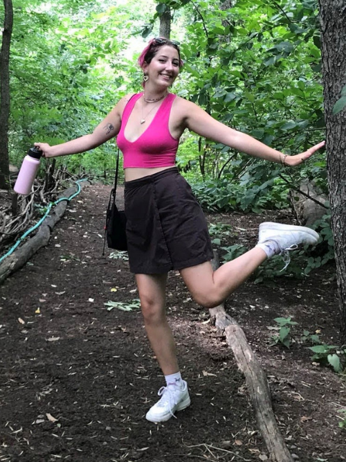 A photo of Lauren outdoors on a trail holding her water bottle and smiling