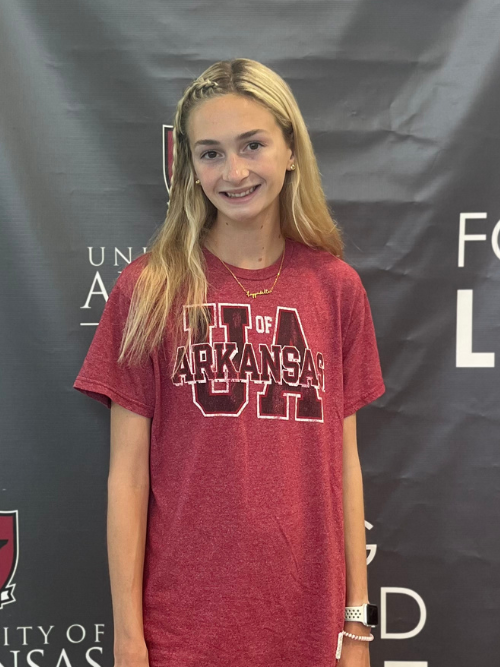Image of Samantha, wearing a University of Arkansas red shirt, with a wide smile, holding her hands by her sides.